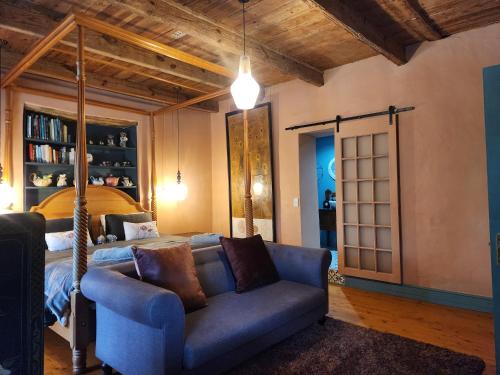 a living room with a blue couch and a bed at Greyton Toad Hall exclusive use up to 18 and by supplement up to 22 with massive pool and hot tub and sometimes we rent individual rooms in Greyton
