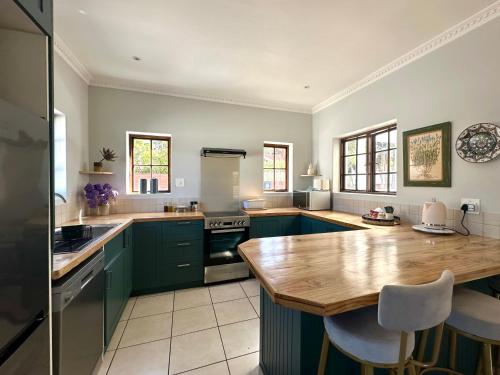 a kitchen with green cabinets and a wooden counter top at Spacious Retreat with Mountain Views in Fish hoek