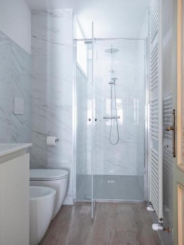 a white bathroom with a shower and a toilet at Design alpino in centro con balcone e parcheggio in Tarvisio