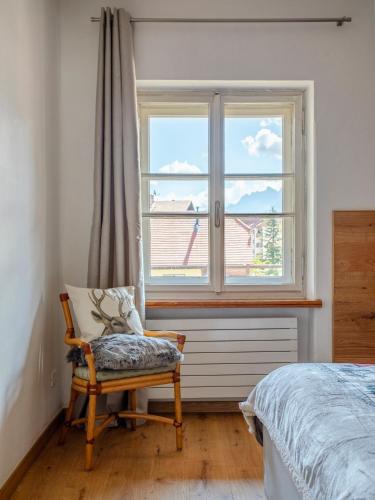 a bedroom with a chair and a window at Design alpino in centro con balcone e parcheggio in Tarvisio
