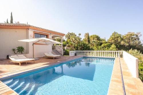 a swimming pool with an umbrella next to a house at Grand Villa! with Golf & Sea view!! in Marbella