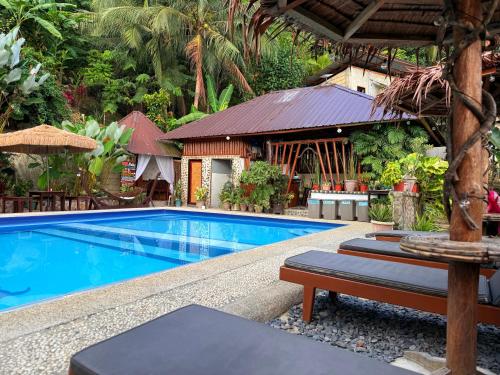 a swimming pool next to a resort with a building at Victordelia Hilltop Hostel in San Vicente