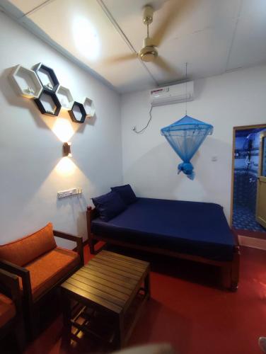a bedroom with a blue bed and a chair at Breeze Guest House in Trincomalee