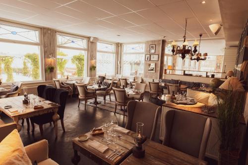a restaurant with tables and chairs and windows at Ystad Saltsjöbad in Ystad