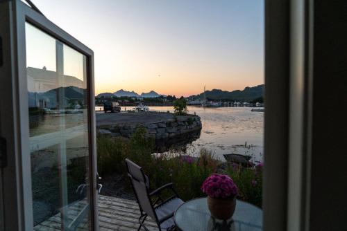 a patio with a table and chairs and a view of the water at Ballstad Tide House - Lofoten in Ballstad