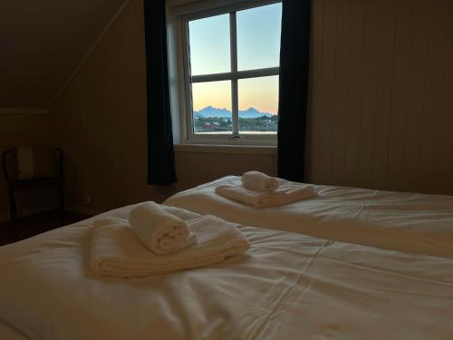 two white towels on two beds in a room with a window at Ballstad Tide House - Lofoten in Ballstad