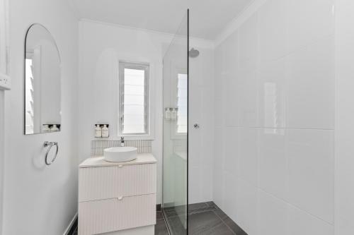 a white bathroom with a sink and a shower at Townsville Suites in Townsville