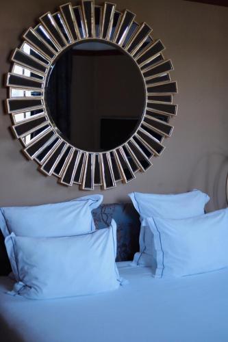 a mirror on a wall above a bed with pillows at Domaine Saint Clair - Le Donjon in Étretat