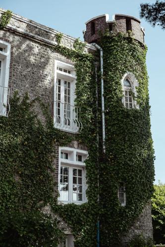 an ivycovered building with white windows and a building at Domaine Saint Clair - Le Donjon in Étretat