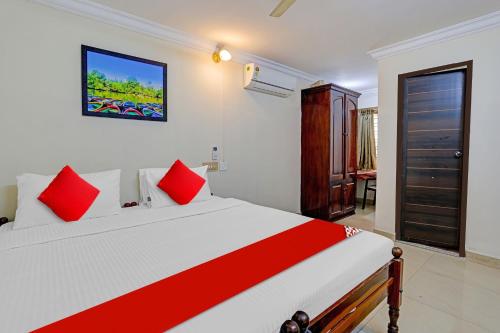 a bedroom with a large white bed with red pillows at Hotel O Le Fort in Trivandrum