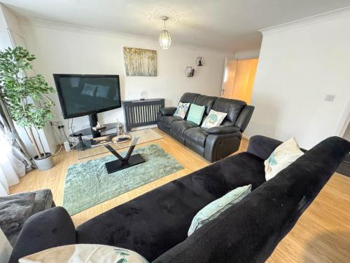 a living room with a black couch and a flat screen tv at Spacious Beautiful London 2 Bedroom Apartment - 2 Bathrooms 1 Parking in London