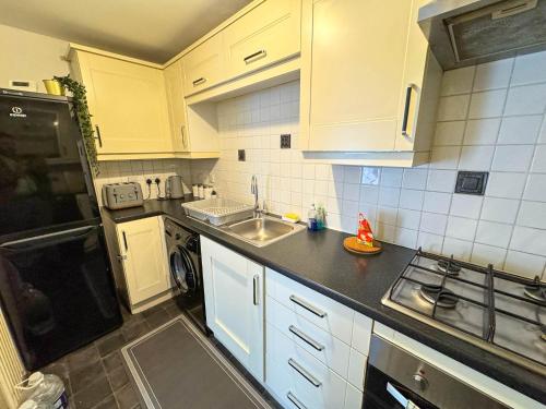 a kitchen with white cabinets and a sink and a stove at Spacious Beautiful London 2 Bedroom Apartment - 2 Bathrooms 1 Parking in London