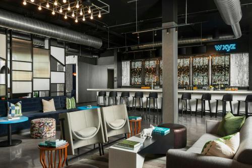 a bar with chairs and a counter with wine bottles at Aloft DFW Airport North in Irving
