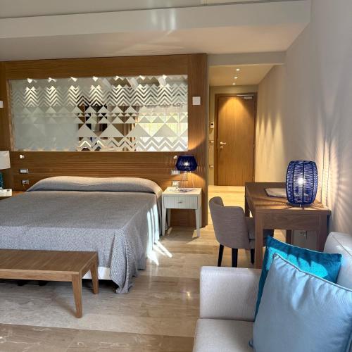 a bedroom with a bed and a table and a couch at Hotel La Bisaccia in Baja Sardinia