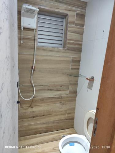 a small bathroom with a toilet and a window at Hostel Família Durães in Londrina