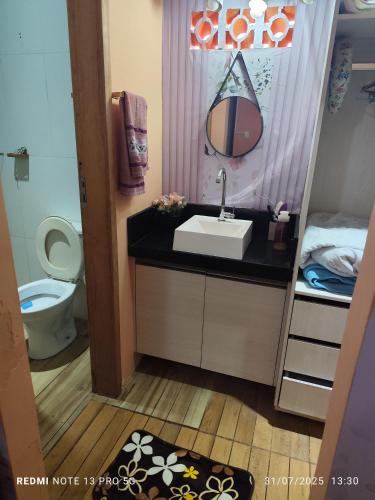 a bathroom with a sink and a toilet and a mirror at Hostel Família Durães in Londrina