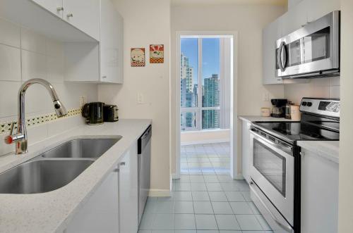 a white kitchen with a sink and a stove at Luxury 3BR Apartment In The Heart Of Downtown - Gorgeous Views! in Vancouver
