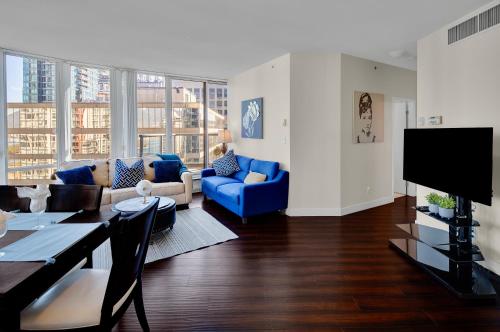 a living room with a blue couch and a table at Luxury 3BR Apartment In The Heart Of Downtown - Gorgeous Views! in Vancouver