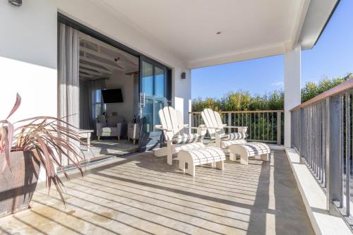 a deck with chairs and a television on a house at Whale Rock Luxury Lodge in Hermanus
