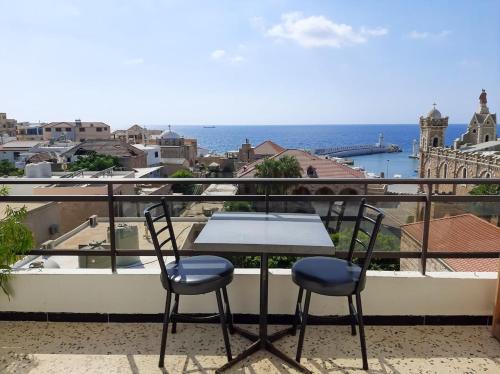 a table and chairs on a balcony with a view of the ocean at Vers Les Nuages Apartment, Old Souk, Sea View in Batroûn