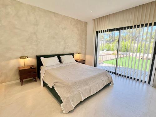une chambre avec un grand lit et une grande fenêtre dans l'établissement Villa Porto-Vecchio avec piscine, à Lecci
