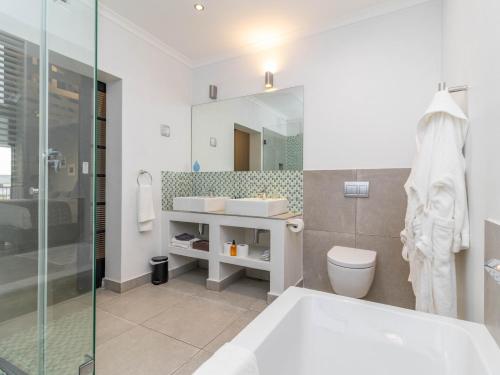 a bathroom with a tub and a sink and a toilet at Whale Rock Luxury Lodge in Hermanus