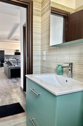 a bathroom with a sink and a living room at Thea Penthouse with private parking in Sarandë