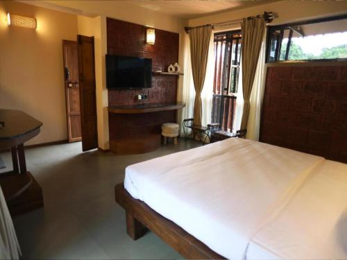 a bedroom with a large white bed and a television at Comfort Cove in Vythiri