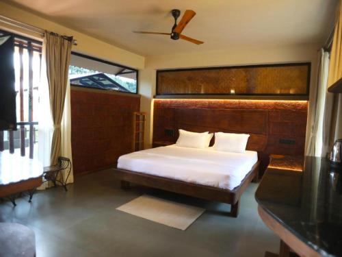 a bedroom with a large bed with a wooden headboard at Comfort Cove in Vythiri