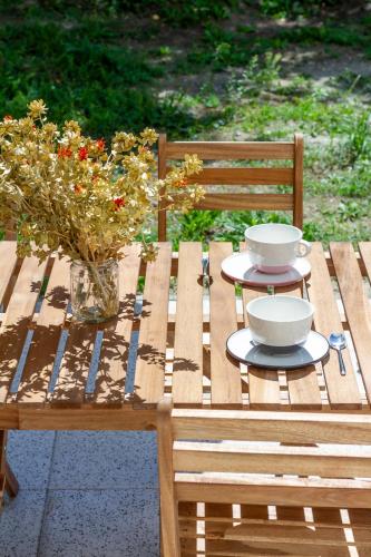 a wooden picnic table with two bowls and flowers on it at BBQ Terrace Balaton 2BR Apt by NW in Balatonszárszó