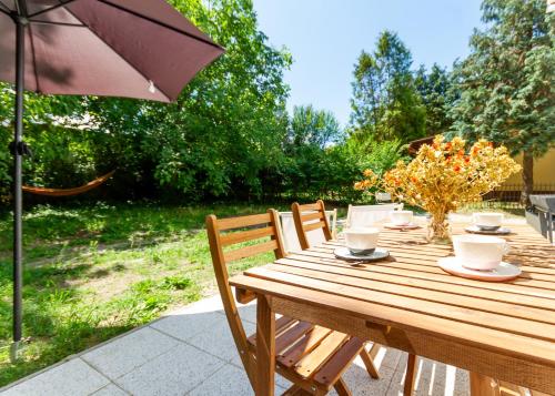 a wooden table with chairs and an umbrella at BBQ Terrace Balaton 2BR Apt by NW in Balatonszárszó