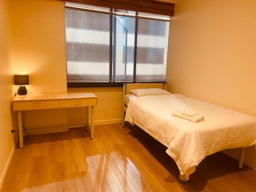 a bedroom with a bed and a desk and a window at Garden Hostel in Auckland