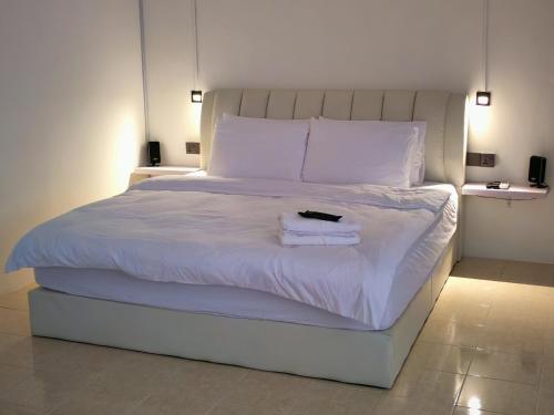 a bed with white sheets and a book on it at 23 Inn Kingbed Room with Balcony in Bukit Mertajam