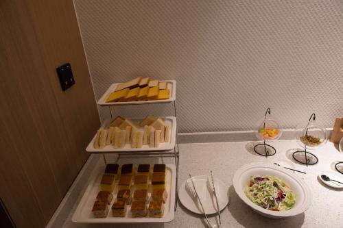 a table with three trays of food and a bowl of salad at Leader Art Hotel（Shenzhen University Science and Technology Park Store)） in Shenzhen