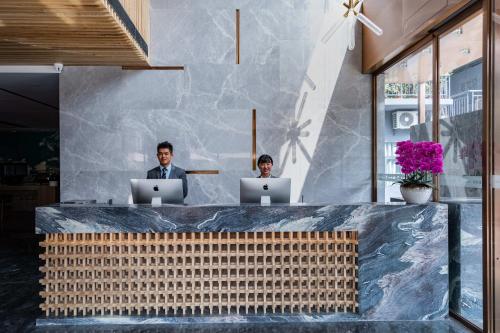 two men sitting at a counter with their laptops at Leader Art Hotel（Shenzhen University Science and Technology Park Store)） in Shenzhen