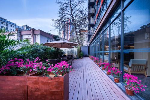 a wooden walkway with flowers and an umbrella on a building at Leader Art Hotel（Shenzhen University Science and Technology Park Store)） in Shenzhen