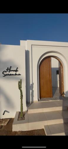 a cactus in front of a building with a door at Houch Saramina in Midoun