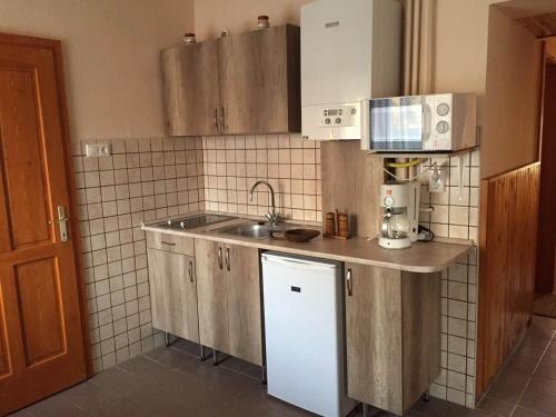 a small kitchen with a sink and a microwave at Vámos Apartman in Bük
