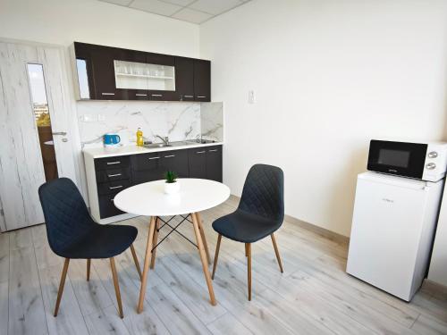 a kitchen with a table and two chairs and a refrigerator at Hotel Slobi in Štúrovo