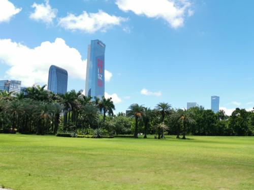 a park with palm trees and a tall building at Leader Art Hotel（Shenzhen University Science and Technology Park Store)） in Shenzhen