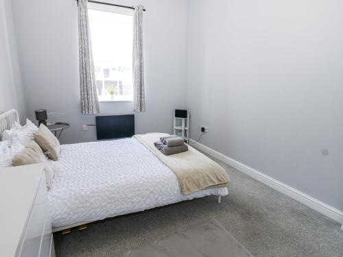 a white bedroom with a bed and a window at Lowther House in Whitehaven