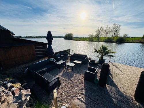 a patio with couches and chairs next to a lake at Chata u Rybníka in Žďár nad Sázavou
