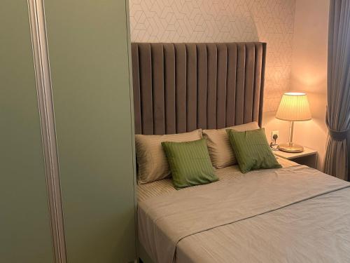 a bedroom with a bed with two green pillows at Canterbury Golf Apartment in Gonapola