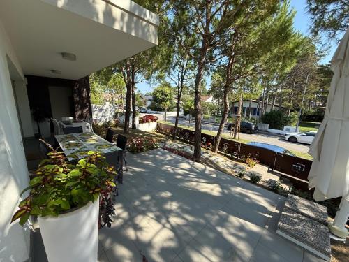a patio with a table and some plants and trees at Villa Pinewood in Lignano Sabbiadoro
