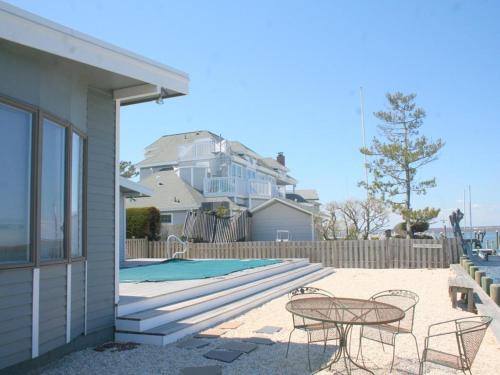 a patio with a table and chairs next to a pool at Bay Front Home In Loveladies, in Loveladies