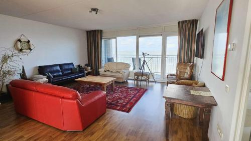 a living room with a red couch and a table at Hello Zeeland - Appartement Port Scaldis 19-031 in Breskens