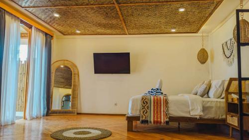 a bedroom with a bed and a tv on the wall at RATU Village - Luxury Apartement & Beachfront Villa Gili Air in Gili Air
