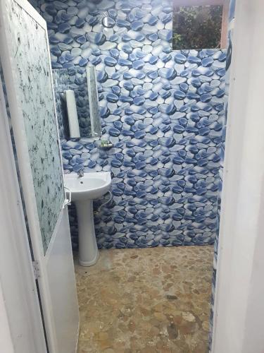 a bathroom with a sink and a blue tiled wall at UK Lounge Resort in Trincomalee