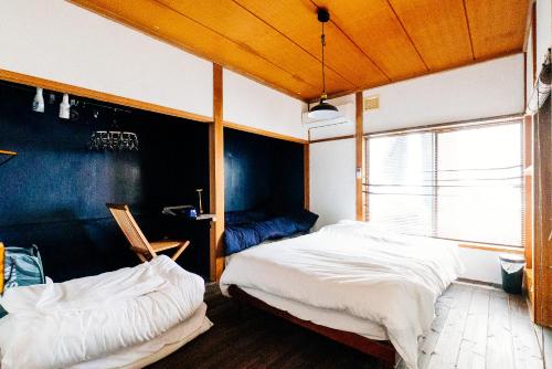 a bedroom with two beds and a window at guesthouse TANDEM in Matsumoto