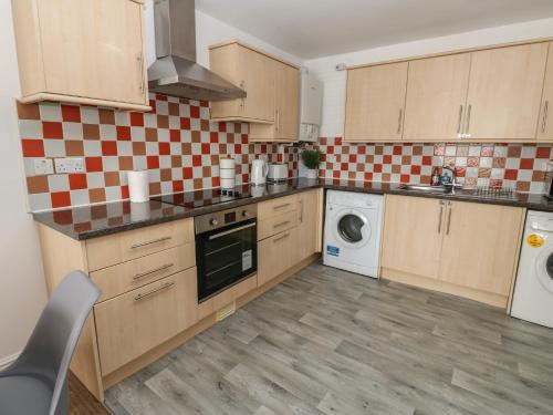 a kitchen with wooden cabinets and a washer and dryer at Curwen Apartment in Workington